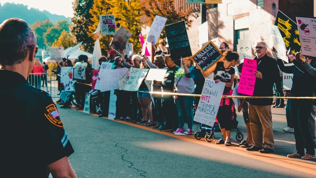 A vibrant protest scene in Wheeling, WV with diverse demonstrators and visible police officer.