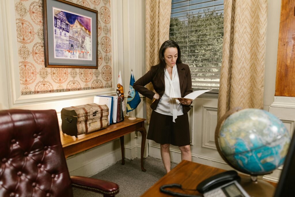 A woman in a professional office setting reviewing documents with focus and intent.